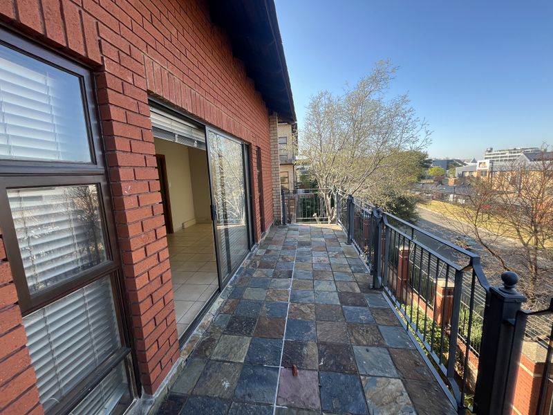 A spacious balcony featuring durable tiled flooring, a secure wrought iron railing, and direct access to the interior through a sliding glass door.