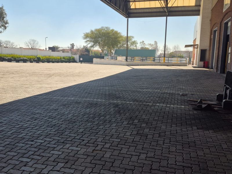 Spacious industrial paved yard featuring a covered loading area and secure perimeter walling, suitable for logistics or storage operations.