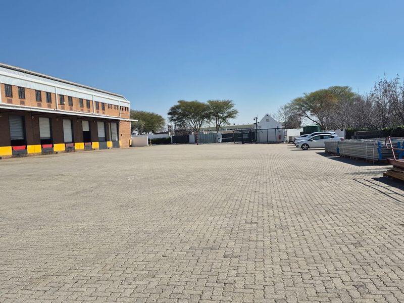 Spacious industrial yard featuring multiple loading docks with roller shutter doors and extensive paved surface area for logistics and vehicle maneuvering.