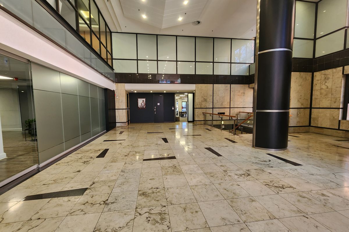 Spacious office building lobby featuring polished marble flooring, modern glass partitions, and high ceilings with integrated lighting.