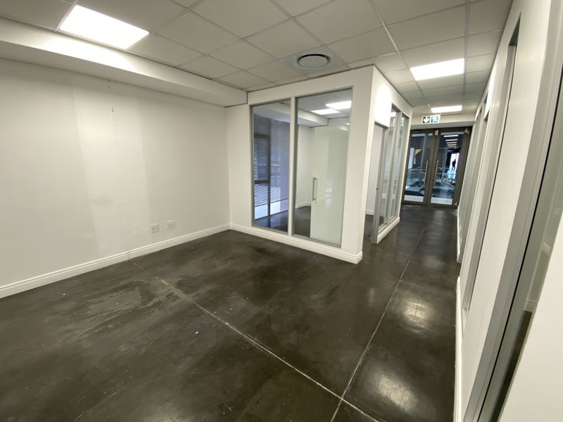 A vacant office space featuring polished concrete floors, glass partitioning, and modern recessed ceiling lighting, offering a clean and professional environment.