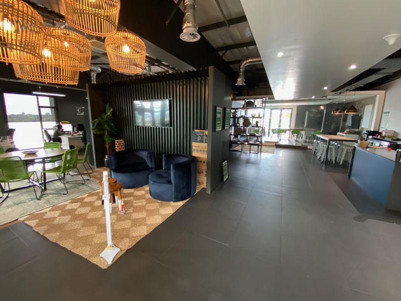 Modern open-plan office space featuring industrial exposed ductwork, a contemporary slatted feature wall, and sleek tiled flooring throughout.