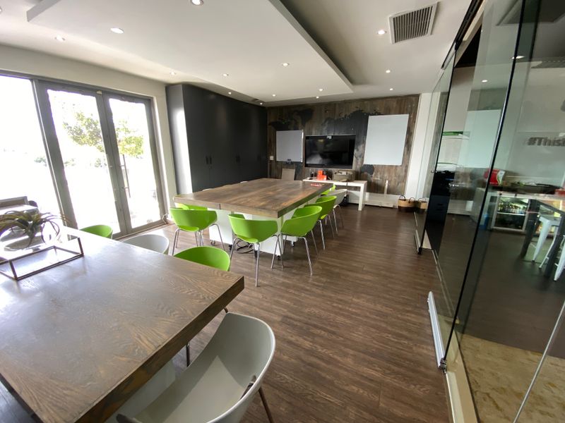 Modern office space featuring laminate flooring, recessed ceiling lighting, built-in cabinetry, and a glass partition wall, providing a professional and functional work environment.