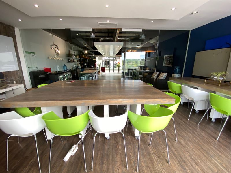 Modern open-plan office space featuring glass partitions, recessed lighting, and durable laminate flooring, creating a bright and professional work environment.