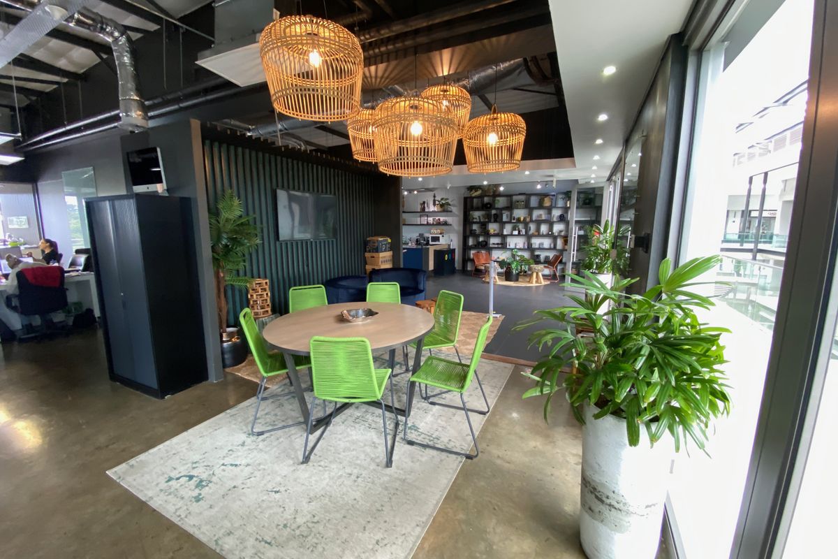 Modern open-plan office space featuring polished concrete floors, exposed industrial ceiling, and a stylish slatted timber feature wall with integrated shelving.