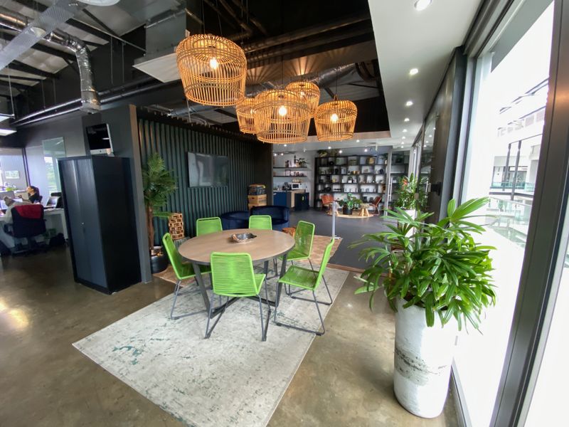 Modern open-plan office space featuring polished concrete floors, exposed industrial ceiling, and a stylish slatted timber feature wall with integrated shelving.