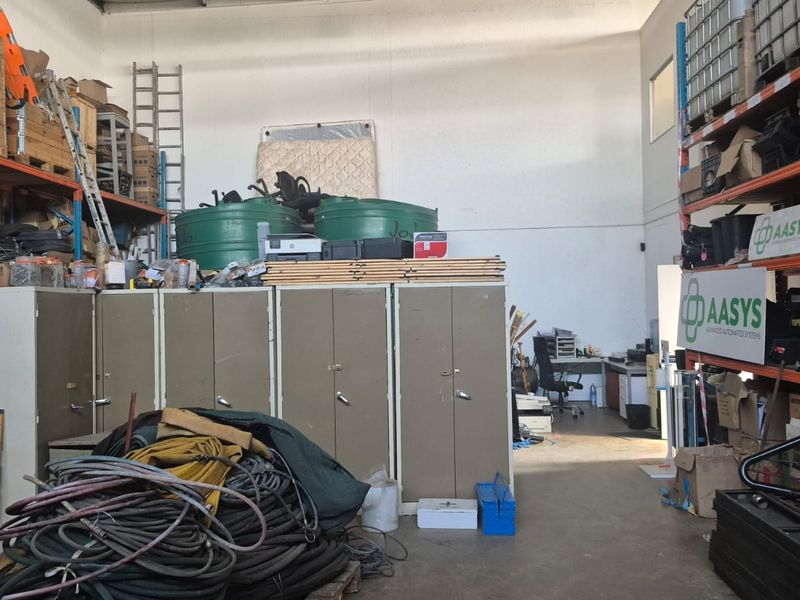 Industrial utility space featuring high-bay ceilings, concrete flooring, and extensive steel racking systems for storage and operational use.