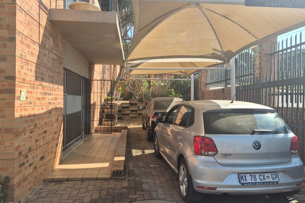 Exterior view of the industrial property featuring a covered parking area with shade sails, brick paving, and secure perimeter fencing.