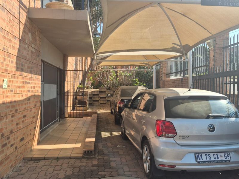Exterior view of the industrial property featuring a covered parking area with shade sails, brick paving, and secure perimeter fencing.