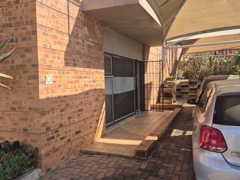 Front exterior view of the industrial property featuring a face brick facade, tiled entrance walkway, and a covered carport area.