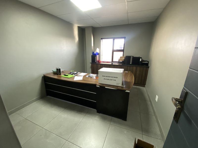 A functional office space featuring tiled flooring, a suspended ceiling, and built-in cabinetry providing ample storage and workspace.