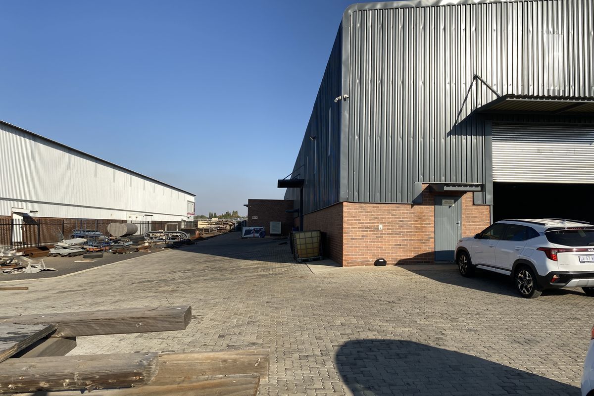 Industrial property exterior featuring a paved yard, corrugated metal cladding, and a roller shutter door access point.