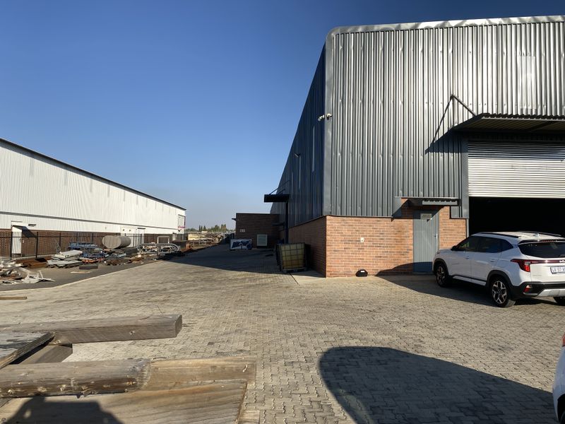 Industrial property exterior featuring a paved yard, corrugated metal cladding, and a roller shutter door access point.
