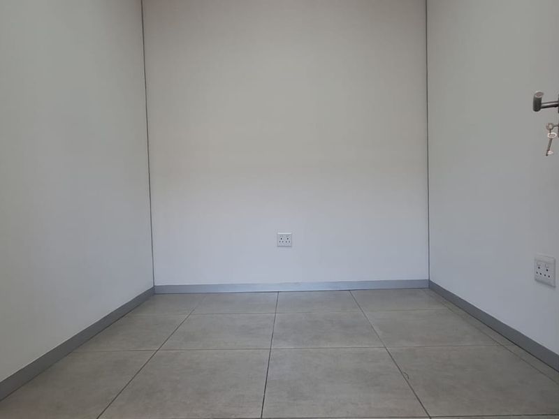 A clean, empty office space featuring neutral tiled flooring, white walls, and integrated electrical outlets, ready for professional fit-out.