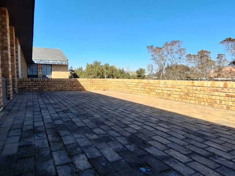 Spacious outdoor balcony featuring brick paving and a low brick boundary wall, offering an open-air space suitable for office break-out or relaxation.
