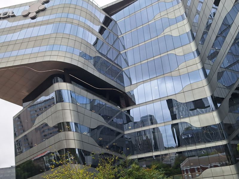 Modern commercial office building featuring a striking glass curtain wall facade and contemporary metal cladding design.