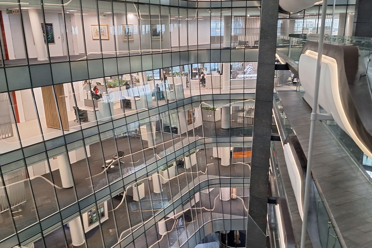 A modern multi-level office building featuring a central atrium with extensive glass partitioning and open-plan workspace layouts.