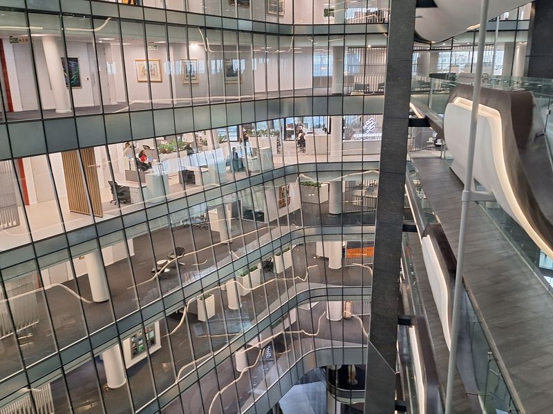 A modern multi-level office building featuring a central atrium with extensive glass partitioning and open-plan workspace layouts.
