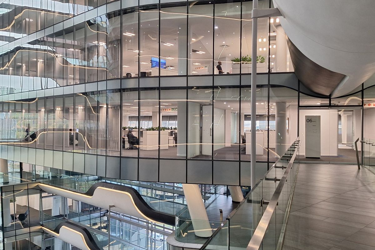 Modern multi-level office atrium featuring extensive glass facades, contemporary architectural design, and open-plan workspace layouts with high-quality finishes.