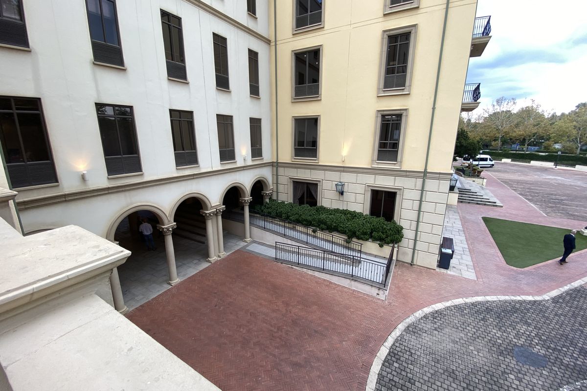 A view of the office building's rear courtyard featuring an arched colonnade, brick paving, and a wheelchair-accessible ramp.