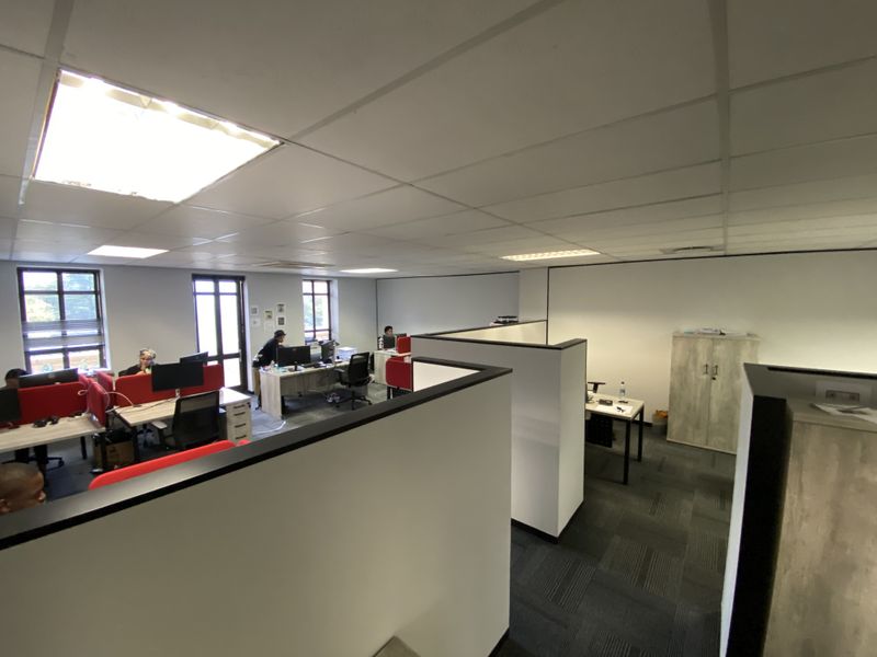 Open-plan office space featuring partition walls, carpeted flooring, suspended ceilings with recessed lighting, and integrated storage cabinetry.