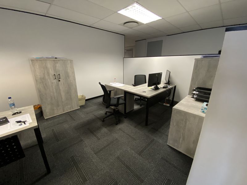 A functional office space featuring carpeted flooring, suspended ceiling with recessed lighting, and built-in storage cabinetry.