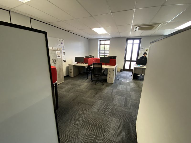 A functional office space featuring carpeted flooring, suspended ceiling with recessed lighting, and integrated air conditioning, providing a professional work environment.