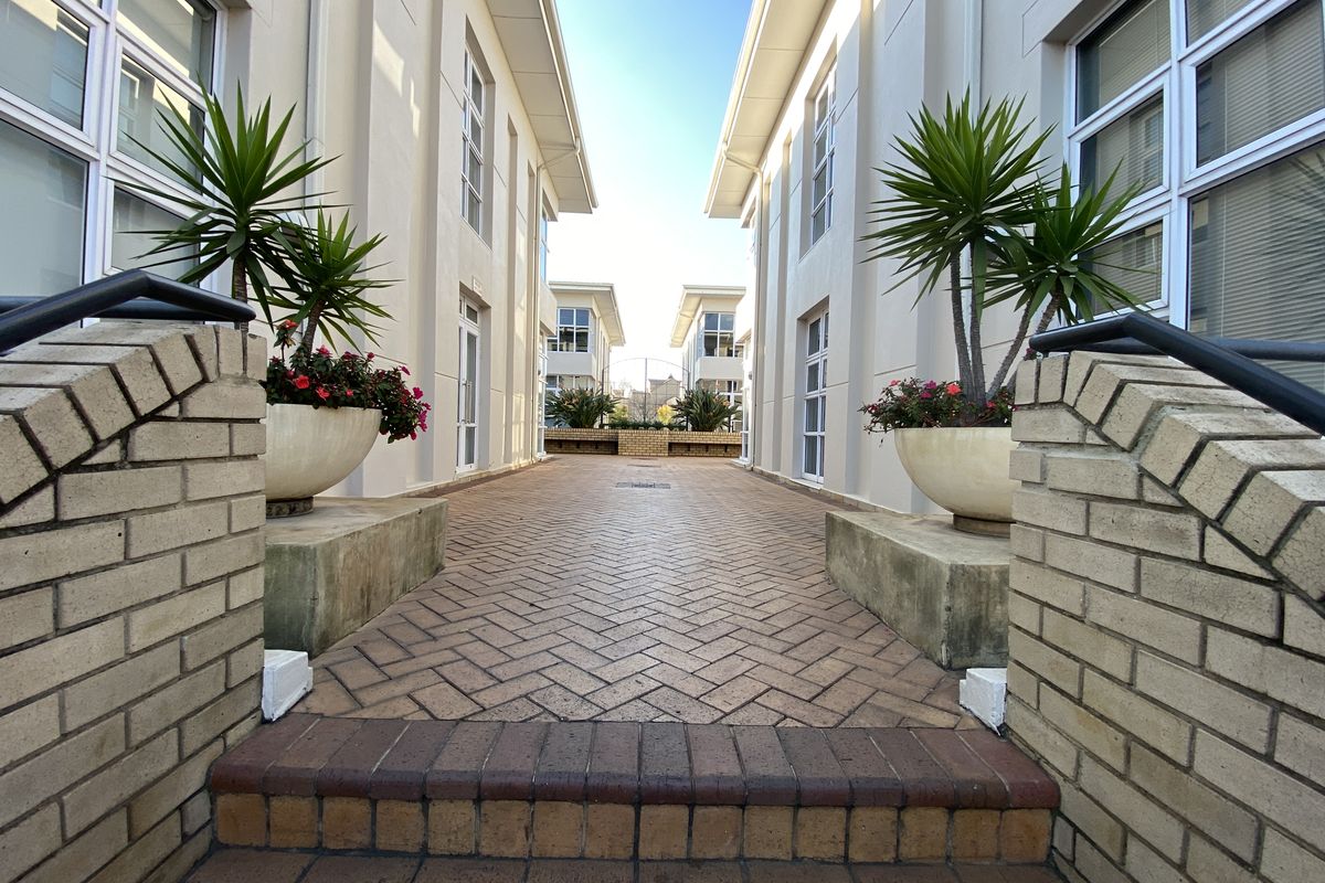 A paved walkway between two office building wings, featuring brick retaining walls and well-maintained exterior finishes.