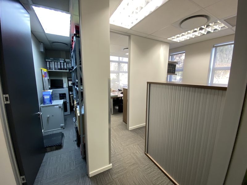 A functional office space featuring carpeted flooring, recessed lighting, and integrated storage solutions, providing a professional and organized work environment.