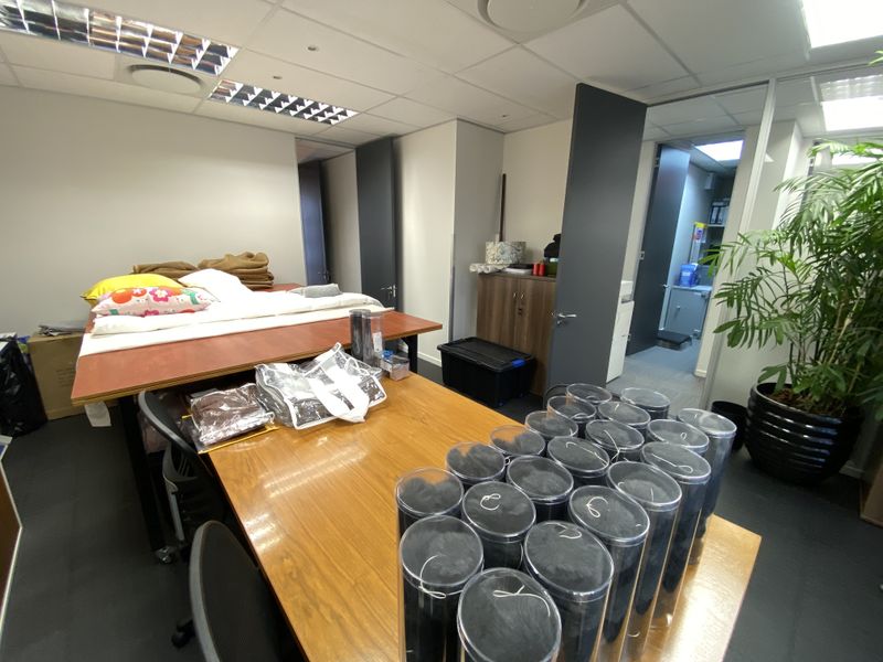 A functional office space featuring a suspended ceiling with recessed lighting, carpeted flooring, and multiple internal doorways leading to adjacent areas.