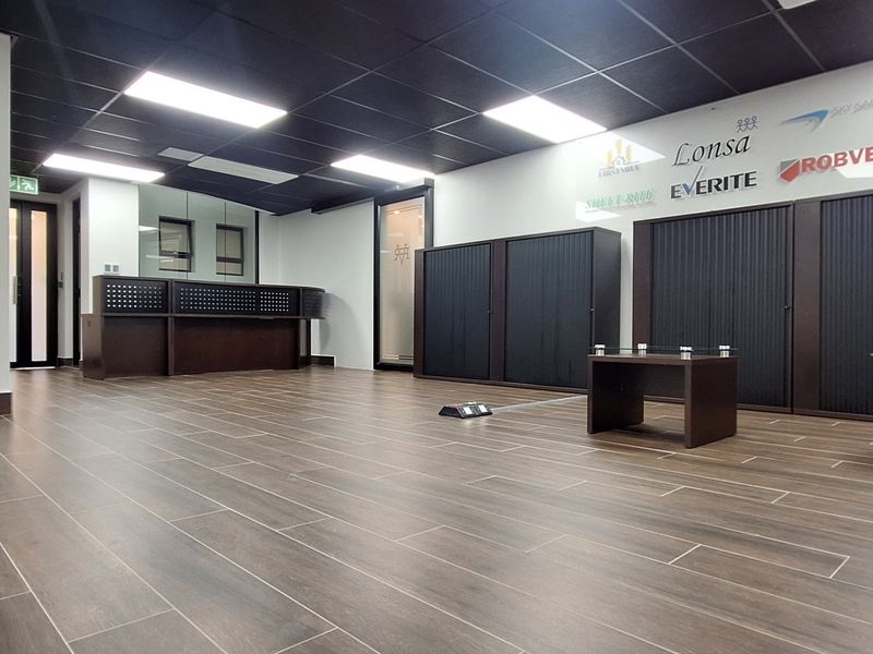 Modern office space featuring wood-look tile flooring, a suspended ceiling with recessed lighting, built-in reception desk, and integrated storage cabinetry.