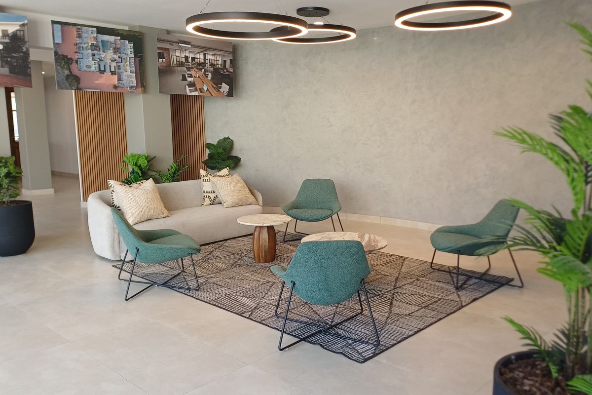 A modern, well-maintained office reception or breakout area featuring contemporary circular pendant lighting, textured feature walls, and elegant slatted wood paneling.