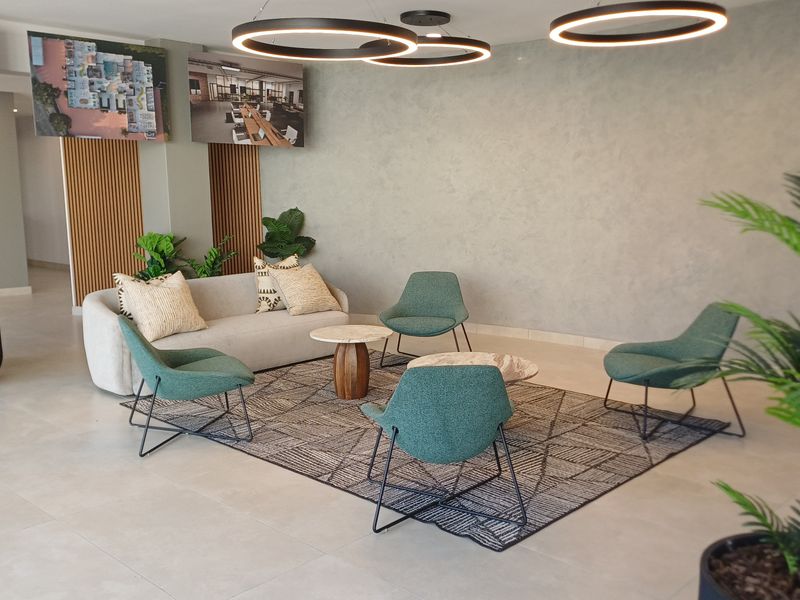 A modern, well-maintained office reception or breakout area featuring contemporary circular pendant lighting, textured feature walls, and elegant slatted wood paneling.