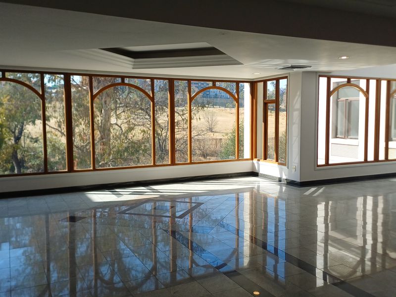 Spacious, sunlit office area featuring polished granite flooring, extensive arched timber-framed windows, and recessed ceiling lighting with integrated air conditioning.