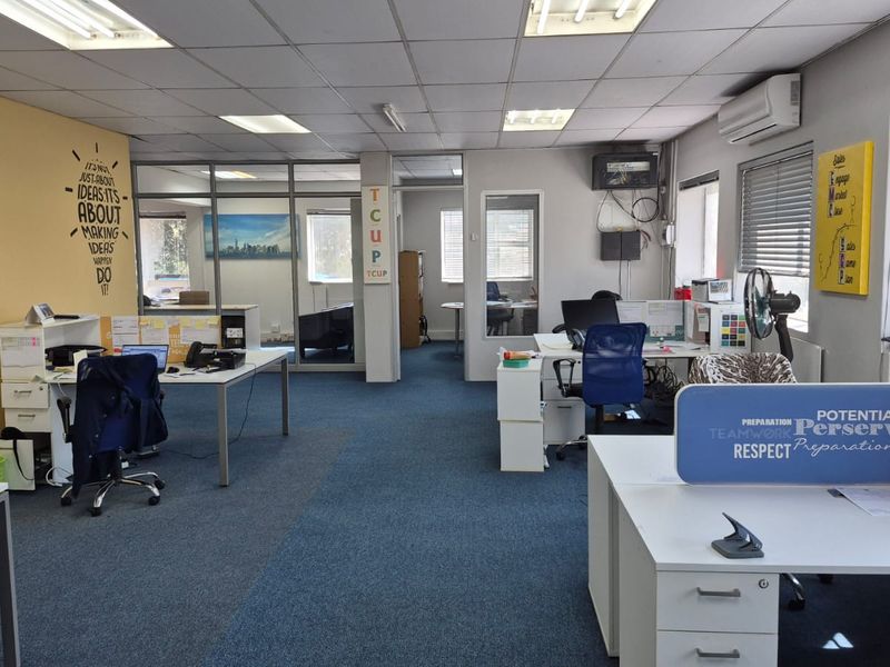 Open plan office space featuring suspended ceilings, air conditioning, and glass partitioned offices with blue carpet flooring.