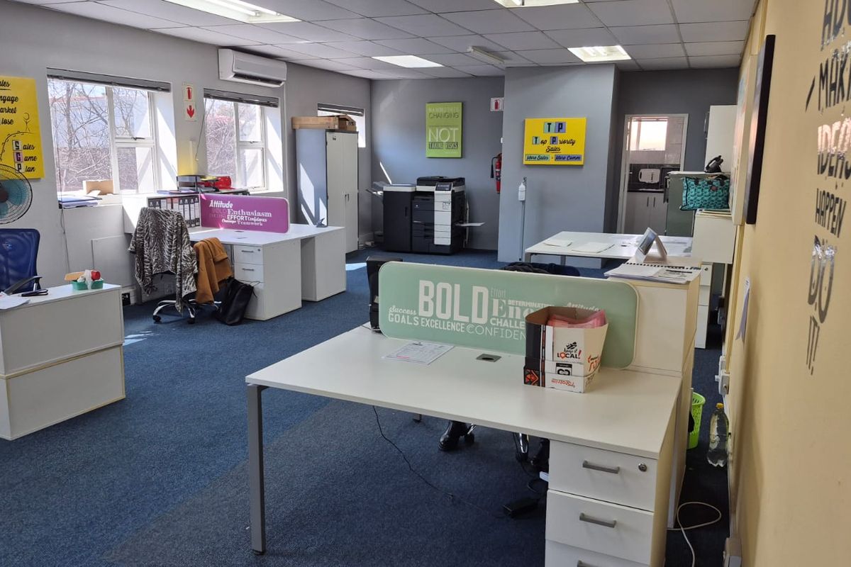 Open-plan office space featuring suspended ceilings, recessed lighting, split-system air conditioning, and carpeted flooring with multiple workstation areas.
