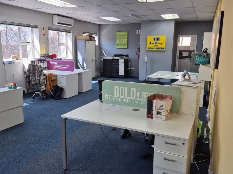 Open-plan office space featuring suspended ceilings, recessed lighting, split-system air conditioning, and carpeted flooring with multiple workstation areas.
