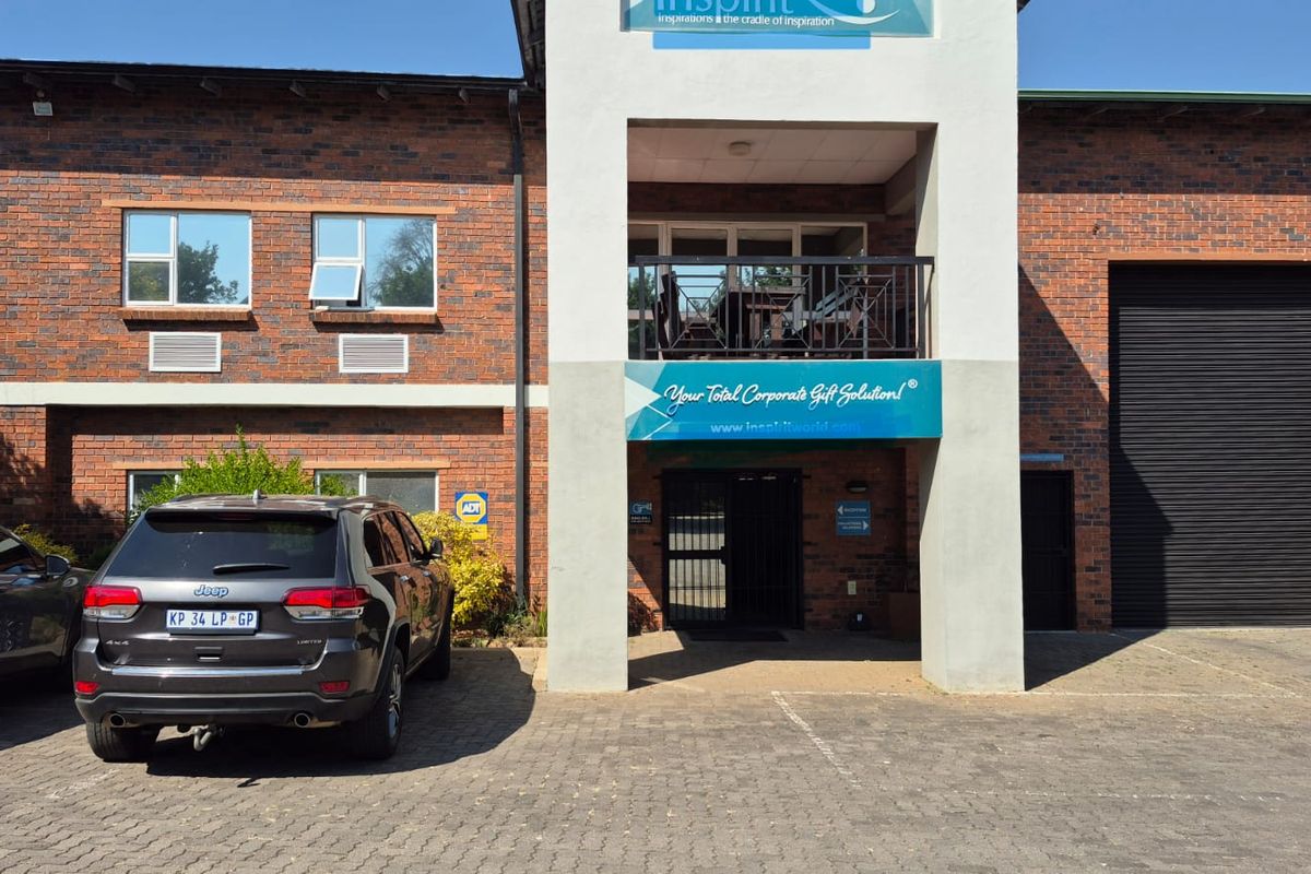 Front elevation of an industrial property featuring a face brick facade, roller shutter door, and a covered entrance with a balcony above.