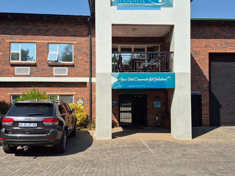 Front elevation of an industrial property featuring a face brick facade, roller shutter door, and a covered entrance with a balcony above.