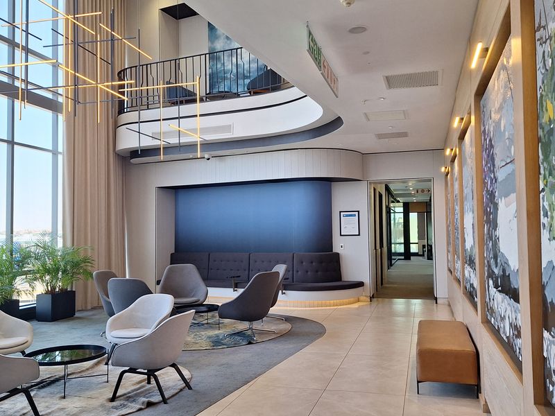 Modern office lobby featuring double-volume ceilings, floor-to-ceiling windows, a mezzanine level, and high-quality finishes throughout.
