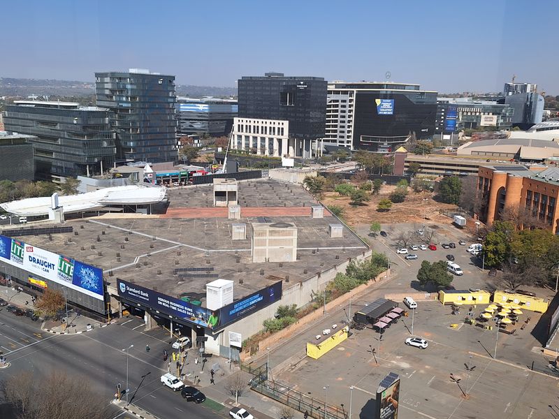 An elevated aerial view overlooking a commercial district with office buildings, parking facilities, and surrounding urban road infrastructure.