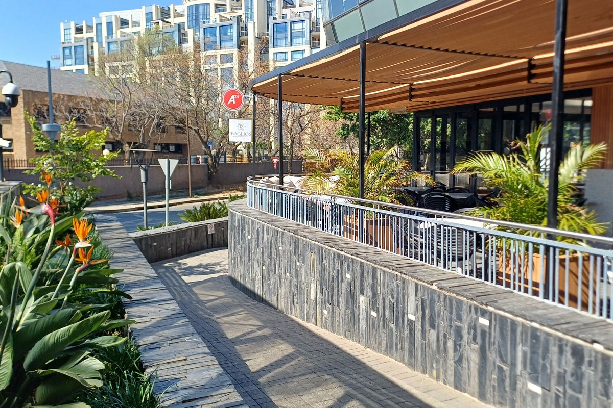 An outdoor patio area featuring stone cladding, a metal safety railing, and a retractable awning, providing a pleasant space for office or commercial use.