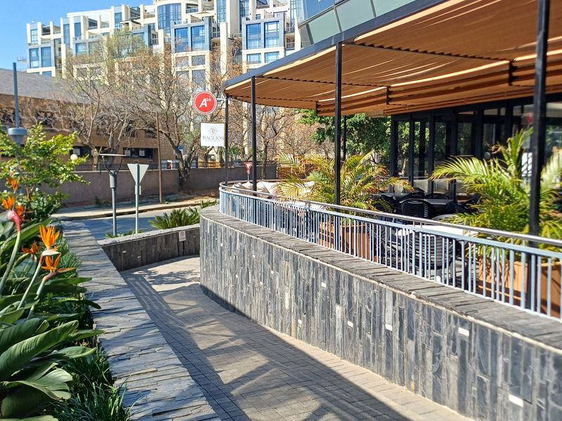 An outdoor patio area featuring stone cladding, a metal safety railing, and a retractable awning, providing a pleasant space for office or commercial use.