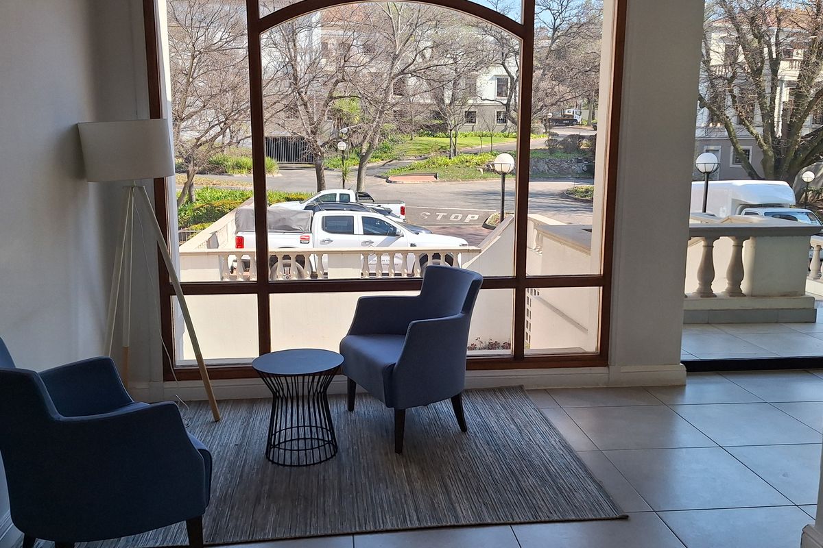 A bright office waiting area featuring large arched windows with views of the exterior, neutral ceramic floor tiles, and a clean, modern aesthetic.