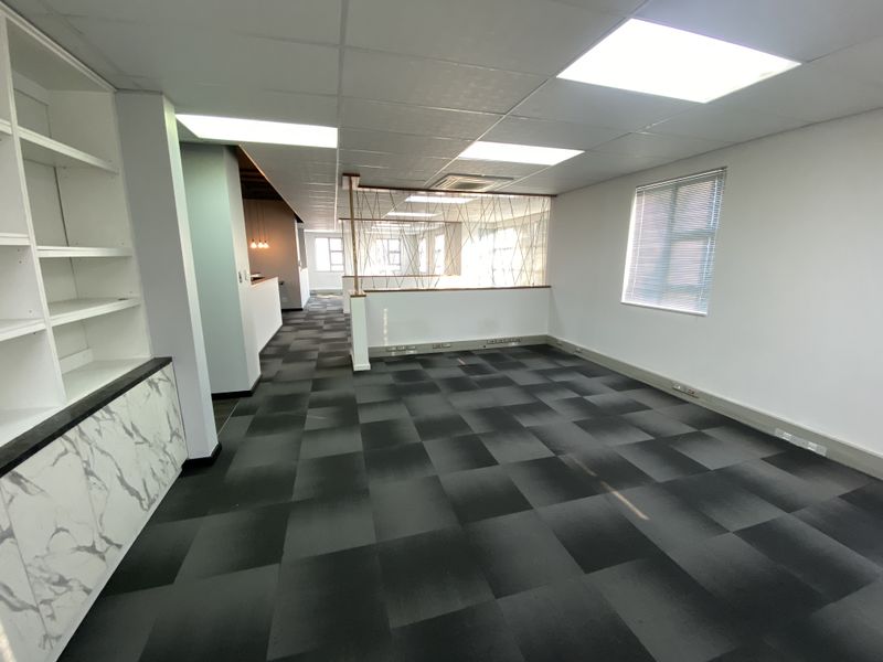 Modern open-plan office space featuring suspended ceilings, recessed lighting, durable carpet tiles, and built-in storage cabinetry with a marble-effect finish.