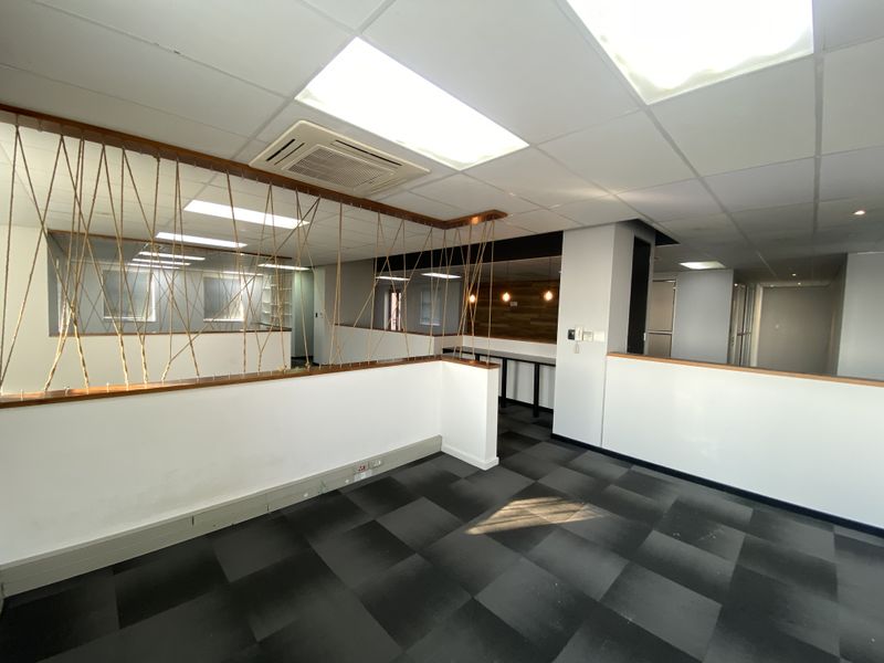 Open-plan office space featuring a suspended ceiling, ducted air conditioning, carpet tiles, and a decorative rope partition divider.