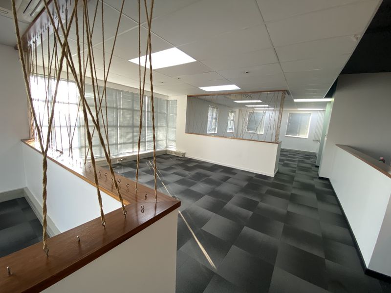 An open-plan office space featuring a suspended ceiling, recessed lighting, and modern carpet tiles, offering a clean and professional environment.