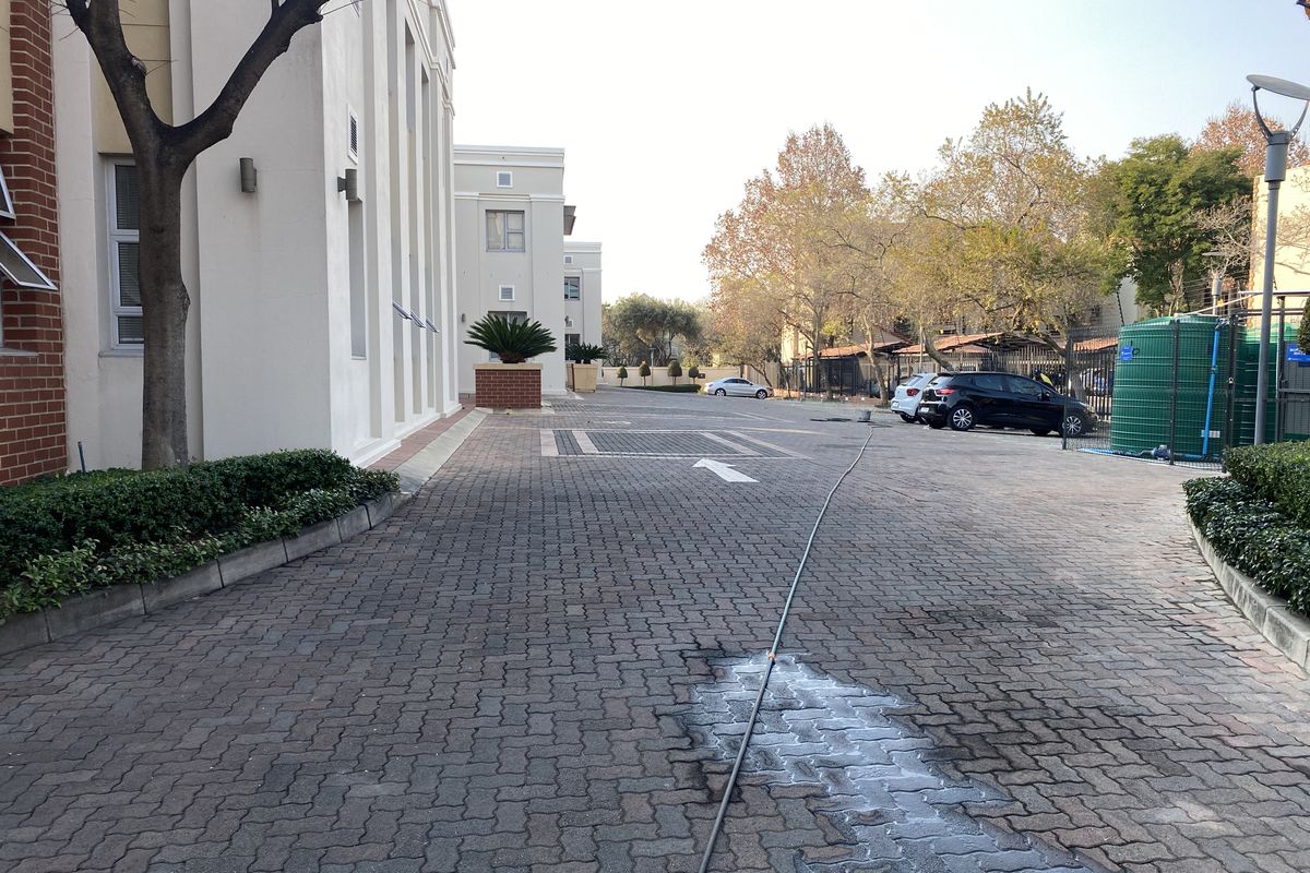 Exterior view of the office property featuring a paved driveway, brick and plaster facade, and a water storage tank in a landscaped setting.