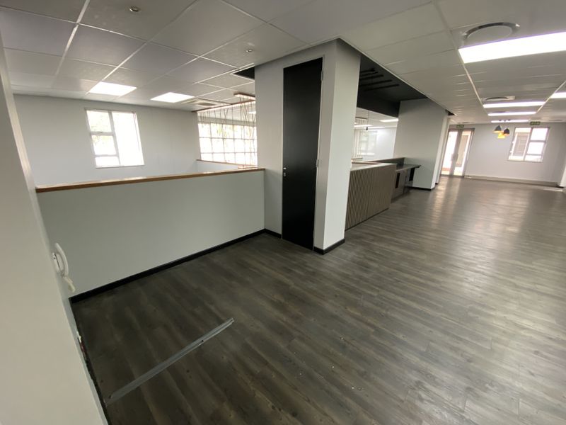 Spacious open-plan office area featuring modern laminate flooring, suspended ceilings with recessed lighting, and built-in cabinetry, offering a clean and professional workspace.