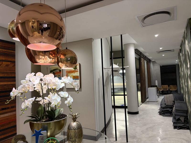 Modern commercial hallway featuring polished concrete floors, recessed lighting, ducted air conditioning, and stylish metal room dividers with sliding barn door access.